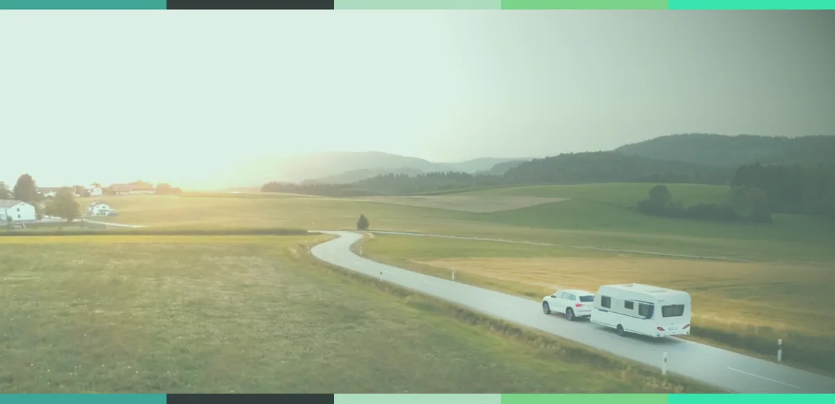 A car towing a caravan along a winding country road